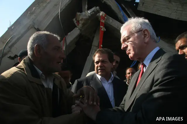 European Union (EU) Parliament President Hans-Gert Poettering (R) hold hands with a Palestinian man during a visit to a Jabalia district that was bombed during Israel's 22-day offensive on the Gaza Strip, on February 23,...