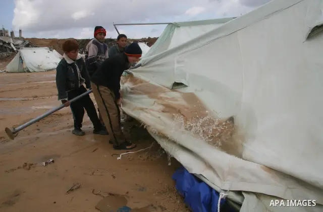 A Palestinian evacuates his belongings from a tent that housed people who had lost their homes during Israel's 22-day offensive, after heavy rain in east of Gaza March 1, 2009. The World Bank said on Sunday it would urge...