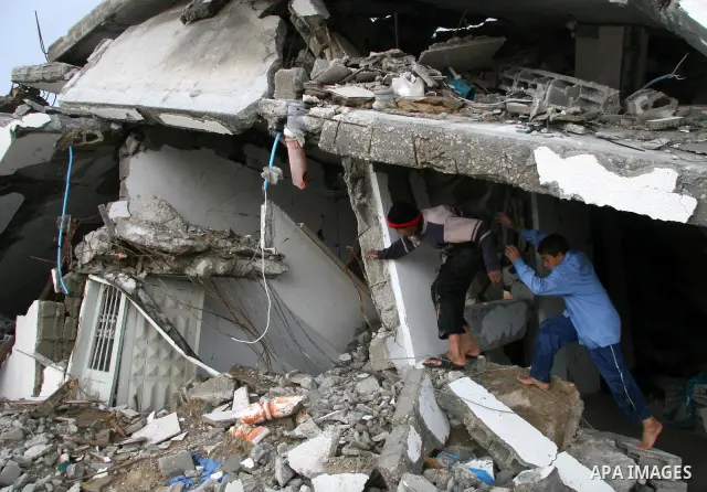 Palestinians walk past a house destroyed during Israel's 22-day offensive, in Jabalya in the northern Gaza Strip March 1, 2009. The World Bank said on Sunday it would urge international financial support for rebuilding t...