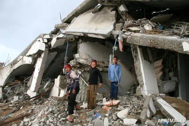Palestinians walk past a house destroyed during Israel's 22-day offensive, in Jabalya in the northern Gaza Strip March 1, 2009. The World Bank said on Sunday it would urge international financial support for rebuilding t...