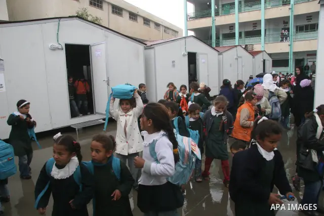 Palestinian students walk on March 15, 2009 past trailers donated by the Dubai-based organization 'Dubai Cares' at their school which was damaged during Israel's 22-day offensive that ended in January, in the northern Ga...
