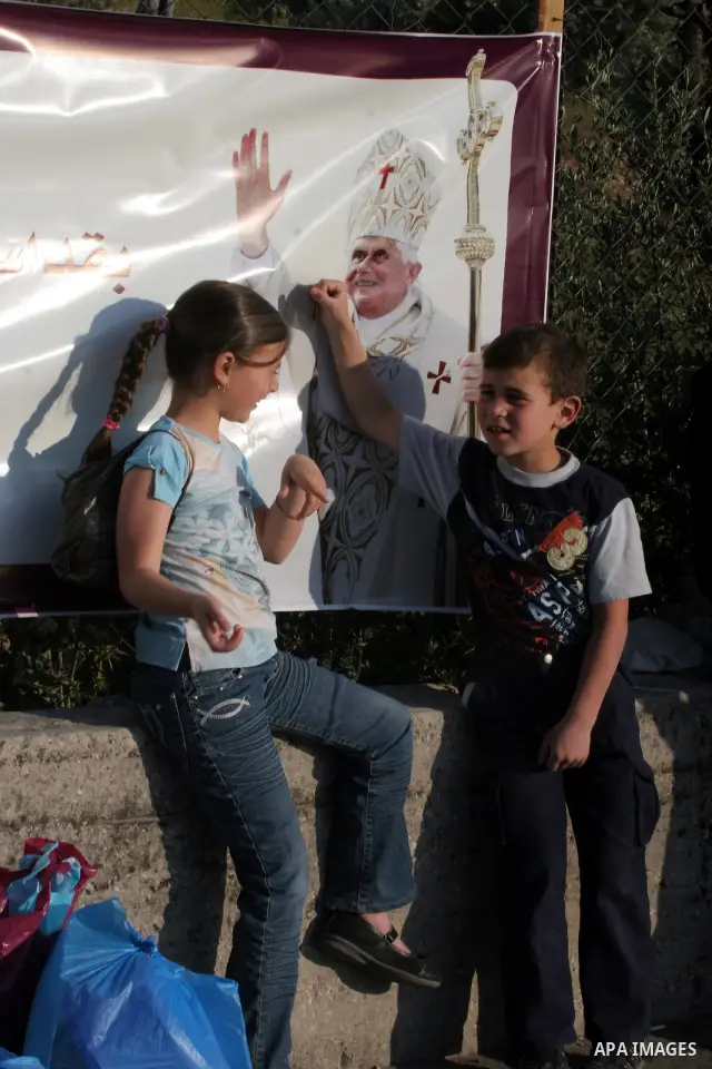 Palestinian children next to a banner showing the image of Pope Benedict XVI, in Bethlehem in the West Bank, monday, May 11, 2009.APAIMAGES PHOTO /Issam rimaw