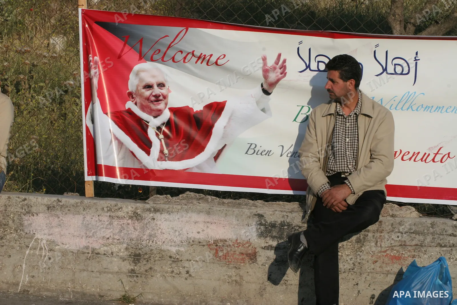 Palestinian Muslim sitting next to a banner showing the image of Pope Benedict XVI, in Bethlehem in the West Bank, Monday, May 11, 2009.APAIMAGES PHOTO /Issam rimawi