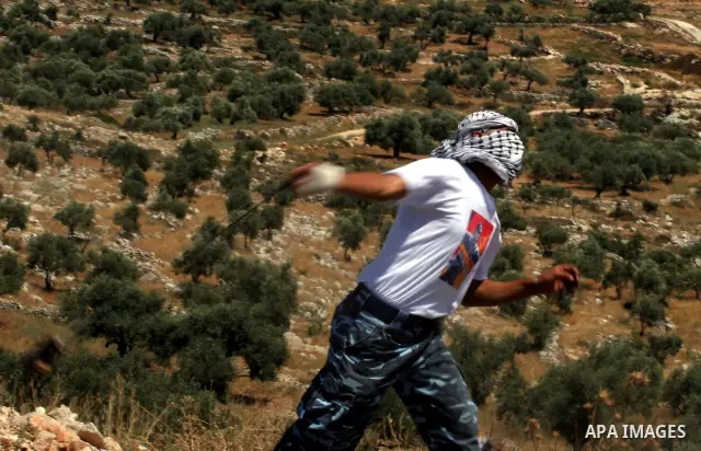 A Palestinian demonstrator uses a sling-shot to hurl stones at Israeli troops during a protest against Israel's separation barrier in the West Bank village of Bilin near Ramallah,May 29, 2009.APAIMAGES PHOTO /Issam rimaw...