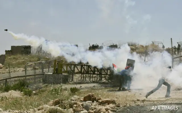 Palestinian demonstrators run for cover with makeshift shields as Israeli soldiers fire teargas during a protest against Israel's controversial separation barrier in the West Bank village of Bilin near Ramallah on May 29...