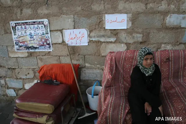 Palestinian girl Intesar al-Samoni, 10, sits next to a poster bearing pictures and names of 29 of her relatives killed during Israel's offensive in the Gaza Strip earlier this year, in al-Zaitoun neighbourhood of Gaza Ci...
