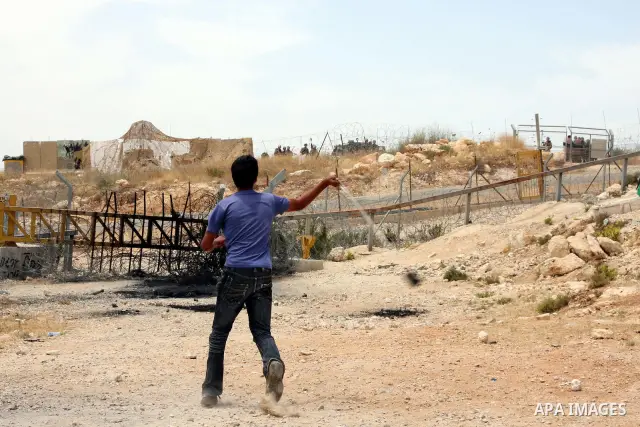 A Palestinian demonstrator uses a sling-shot to hurl stones at Israeli troops during a protest against Israel's separation barrier in the West Bank village of Bilin near Ramallah,June 4, 2009. PHOTO/Issam rimawi