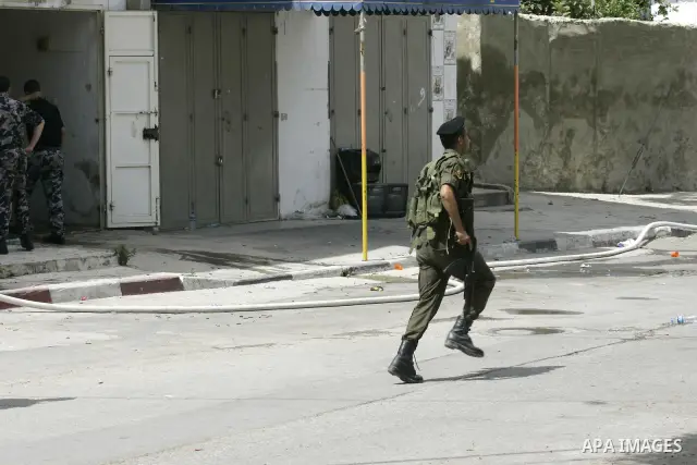 Palestinian security officers take position during a raid against Hamas gunmen in the West Bank town of Qalqiliya, Thursday, June 4, 2009. Three Hamas fugitives in Qalqiliya have opened fire on Palestinian police, killin...