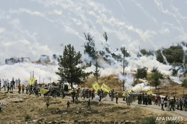 Palestinian and Israeli protesters run from tear gas fired by Israeli troops during a demonstration against Israel's separation barrier in the West Bank village of Bilin near Ramallah, outside the Jewish settlement of Md...