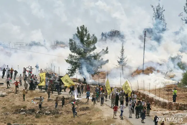 Palestinian and Israeli protesters run from tear gas fired by Israeli troops during a demonstration against Israel's separation barrier in the West Bank village of Bilin near Ramallah, outside the Jewish settlement of Md...