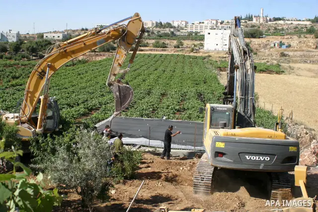 Israeli soldiers stand guard as a bulldozer demolish Palestinian pool near of Kharsina settlement in the West Bank city of Hebron, June 08, 2009. Photo\Najeh Hashlamoun.