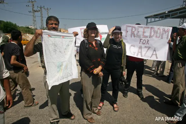 Palestinians hold a national flag and signposts during a protest against the Israeli blockade of Gaza near Erez crossing, northern Gaza Strip, June 9, 2009. Israel has faced growing international calls, including by main...