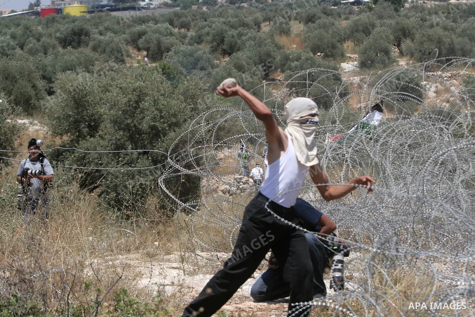 Palestinian protesters throw stones at Israeli soldiers , during a demonstration against Israel's controversial separation barrier in the West Bank village of Bilin, near Ramallah,Friday, June 12, 2009. Photo/Nedal Shtie...