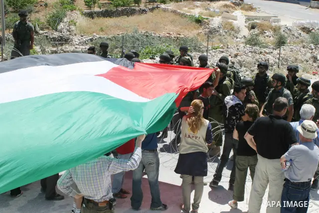 Israeli soldiers (back) monitor a demonstration by Palestinian and foreign protestors against the construction of the Israeli separation barrier in the village of Maasarah, near the West Bank town of Bethlehem, on 12 Jun...