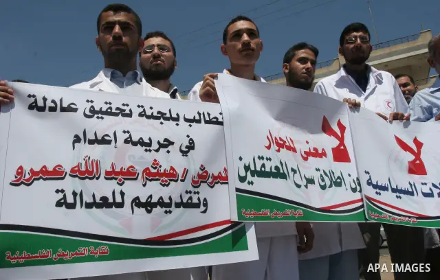 Palestinian Members of nursing syndicate hold placards as they attend a protest against the killing of their colleague Haysam Amro by the security forces of the Palestinian authority in the West Bank, In Gaza City on jun...