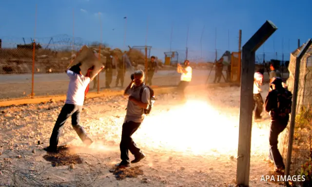 An Israeli soldiers fire tear gas against Palestinian and foreign protesters during a demonstration against Israel's controversial separation barrier in the West Bank village of Bilin near Ramallah on July3,2009. Photo b...