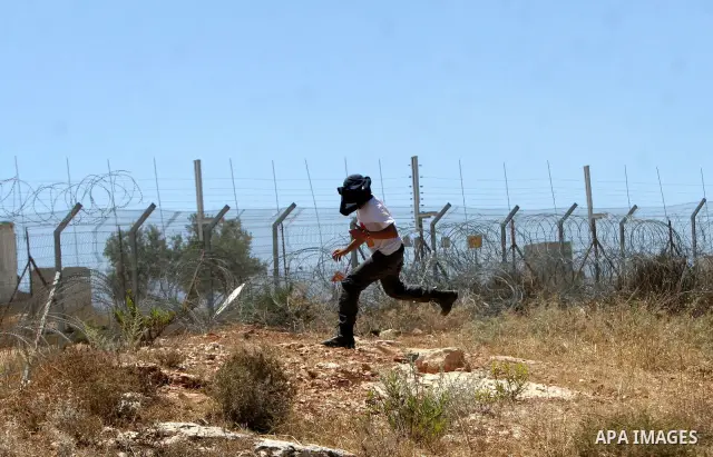 A Palestinian and foreign protesters clash with Israeli soldiers during a demonstration against Israel's controversial separation barrier in the West Bank village of Bilin near Ramallah on July3,2009. Photo by Nedal Shti...