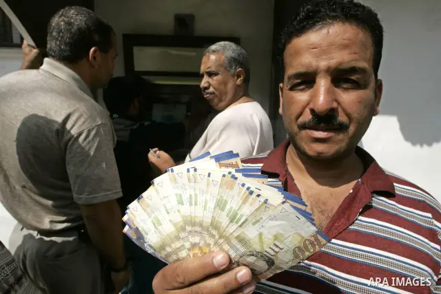A Palestinian man displays his money after withdrawing it from an automated teller machine (ATM) of the Bank of Palestine in Rafah in the southern Gaza Strip on July 6, 2009. The Palestinian National Authority (PNA) is p...