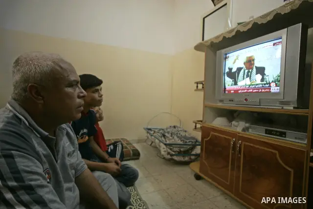 Palestinians from the Gaza Strip listen to Palestinian president Mahmud Abbas as he delivers a speech during the Fatah congress in the West Bank city on Bethlehem, on August 4, 2009 in the southern Gaza Strip town of Raf...