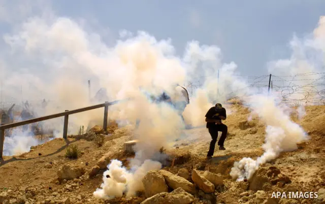 Palestinian and foreign protestors run away from tear gas threw by Israeli soldiers during a demonstration against Israel's controversial separation barrier in the West Bank village of Bilin near Ramallah on Aug 7, 2009....