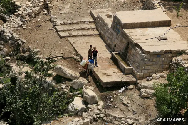 A young Palestinian boys carries bottles of water on a donkey in the West Bank village of Qarawah Bani Zeid on August 8, 2009. According to the World Bank, the Palestinians have limited access to potable water, especiall...