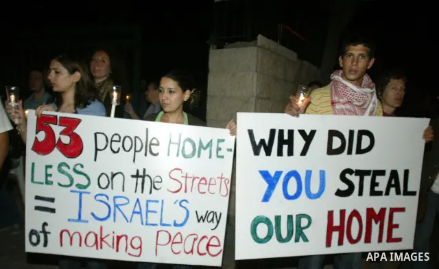 Demonstrators hold a sign as Israeli and foreign peace activists join Palestinians in a candlelight vigil in the east Jerusalem neighbourhood of Sheikh Jarrah on August 10, 2009 to protest against the eviction of two Pal...
