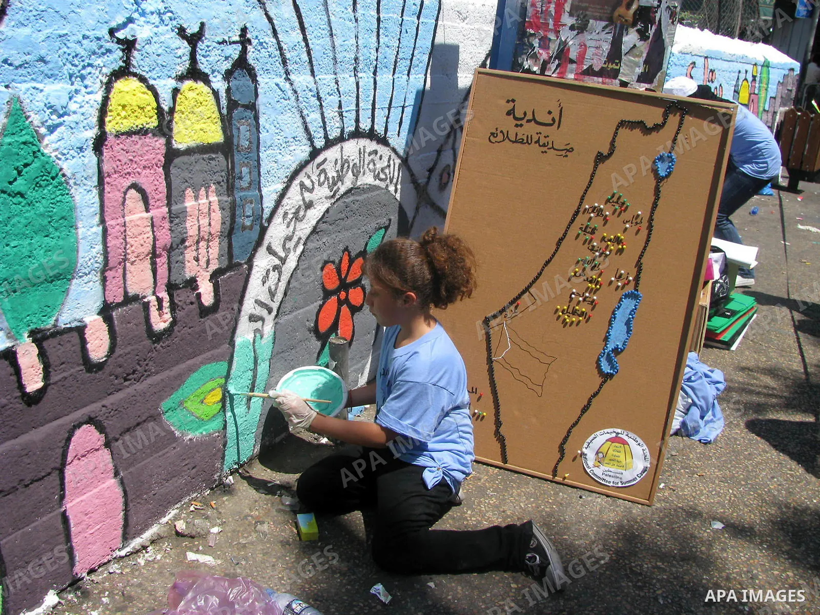 A Palestinian girl paints a wall depicting Jerusalem and the Palestinian flag in the West Bank city of Ramallah on August 12, 2009. Photo by Issam Rimawi