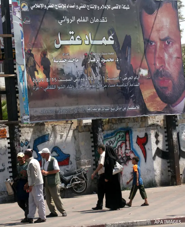 Palestinians walk next a placard of "Emad Akel" film in Gaza City on Aug 12, 2009. Photo By Ashraf Amra