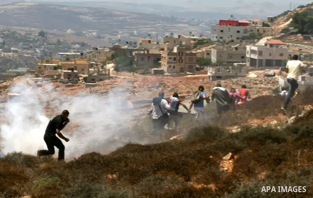 Palestinians runs to take cover from tear gaz fired by Israeli soldiers during a protest against the confiscation of land by the Jewish settlement of Bracha in the West Bank village Burin, near Nablus on Aug 14, 2009. Ph...