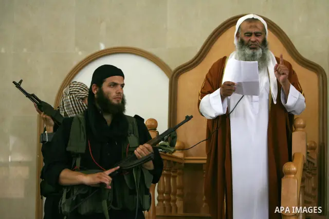 Abdel Latif Musa, a representative the radical Palestinian Islamist group Jund Ansar Allah, is guarded by an armed member of his radical group as he delivers the Friday prayer sermon at a mosque in the southern Gaza Stri...