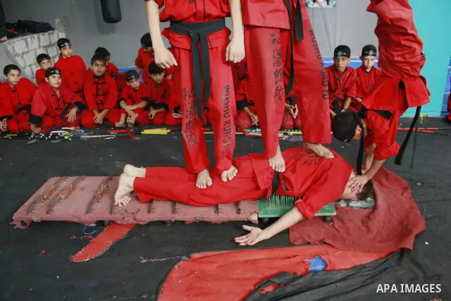 Palestinian boys stand on top of another as he lays on iron nails, broken glass and knives during a training session at the Red Dragon martial arts club in Beit Lahia, northern Gaza Strip, on August 19, 2009. Since the I...