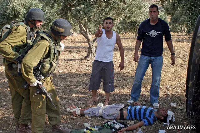 An Israeli soldiers and Palestinian paramedics relief to injured Palestinians, after a traffic accident near the West Bank city of Hebron , 21 August 2009. Photo by Najeh Hashlamoun