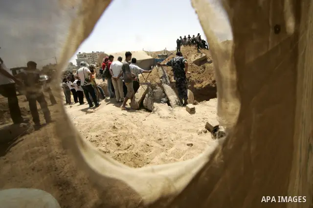 Palestinians and Hamas policemen gather at the spot where one man was killed and five others were reported missing following an Israeli raid on smuggling tunnels in Rafah between Gaza and Egypt on August 25, 2009. Medics...