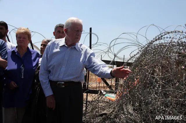 The Elders, a group of eminent global leaders And Former U.S. President Jimmy Carter stands in front of the controversial Israeli barrier during a visit to the West Bank village of Bilin near Ramallah August 27, 2009. Th...