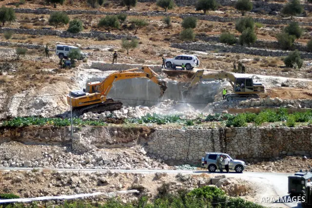 Israeli soldiers stand guard as a construction vehicle destroys a man-made reservoir on a Palestinian farm near the West Bank city of Hebron September 03, 2009. According to Israel's Civil Administration, the reservoir w...