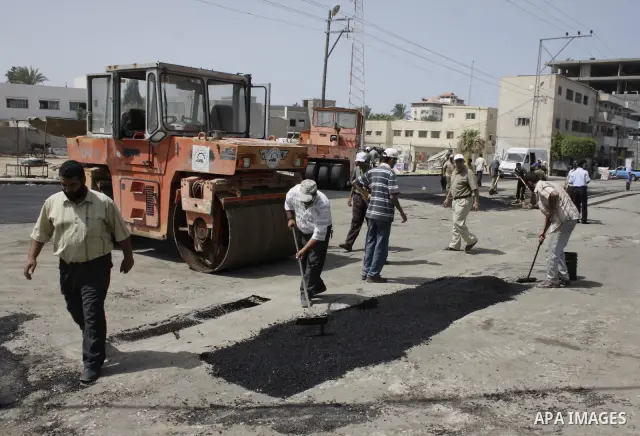 A Palestinian workers pave a road in Khan Younis in the southern Gaza Strip Sep 12, 2009. Frustrated by the lack of outside help, the Islamist group Hamas has begun repairing roads in Gaza using cement and tar smuggled t...
