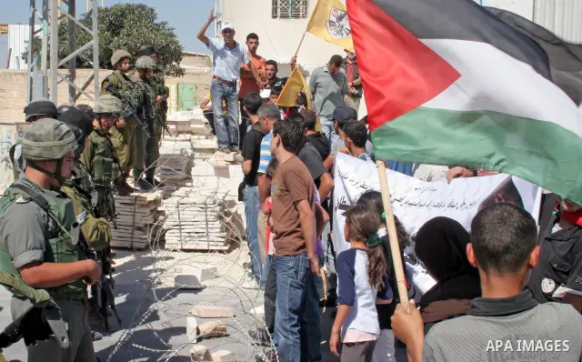 Israeli soldiers stand guard behind razor-wire during a rally by Palestinian and foreign protestors against Israel's separation barrier in the West Bank village of Maasarah, near Bethlehem, on Sep 25, 2009. Photo by Naje...