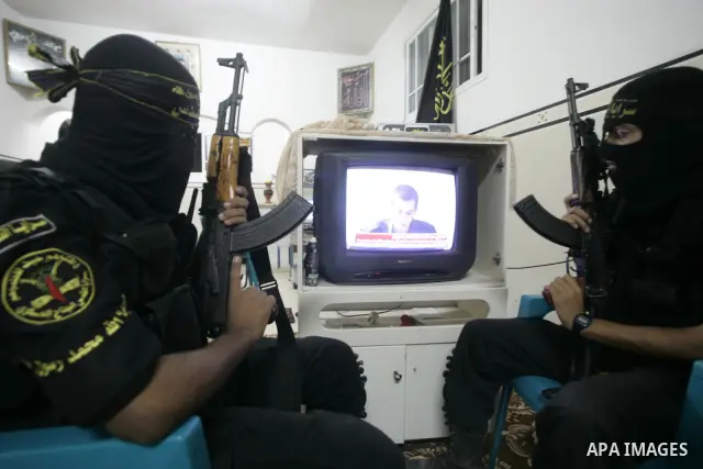 Palestinian Islamic Jihad militants wear masks to conceal their identities as they watch the video tape of a captive, Corporal Gilad Shalit on television during the news bulletin in Rafah, southern Gaza Strip on October...