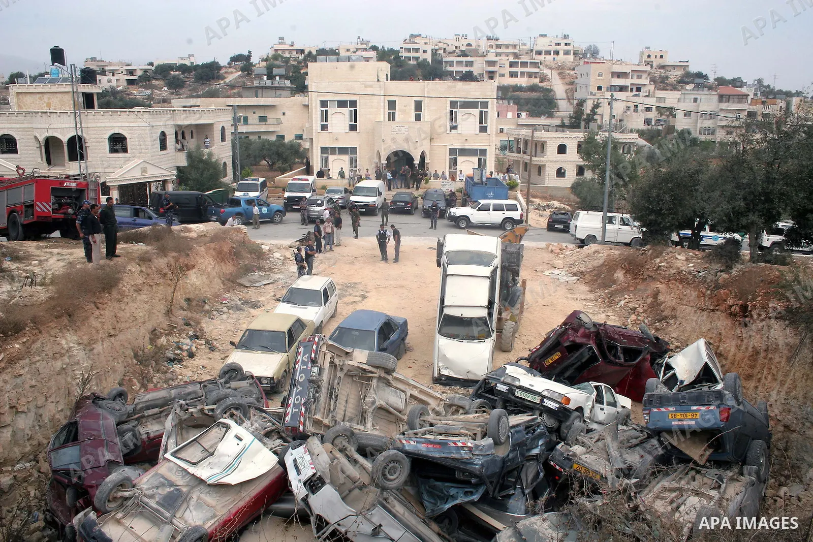 Palestinian policemen stand guard as a bulldozer destroys stolen cars during a continuing crackdown on stolen vehicles, illegally brought into the Palestinian territories in the West Bank town of Beit Fajjar near Bethleh...