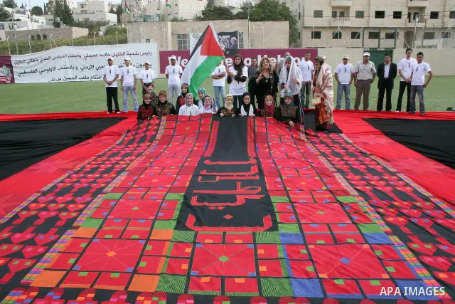 Palestinians display the largest traditional Palestinian dress it will be to create the largest traditional Palestinian dress in an attempt to enter the Guinness World Records at Al-Hussein stadium in the West Bank city...