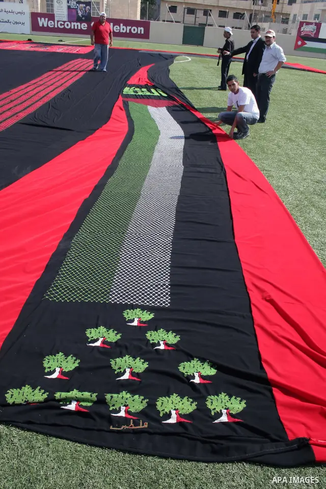 Palestinians present a huge traditional embroidered dress to the media at a football stadium in the West Bank town of Hebron on October 25,2009 with the aim of securing a Guinness world record for the biggest Palestinian...