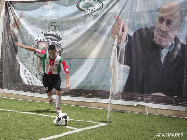 Player of the team Velstino Chile is preparing to hit the ball from the corner in front of a poster of later Palestinian leader Yasser Arafat and General Rajoub during a friendly game between Hebron Youth Club for junior...