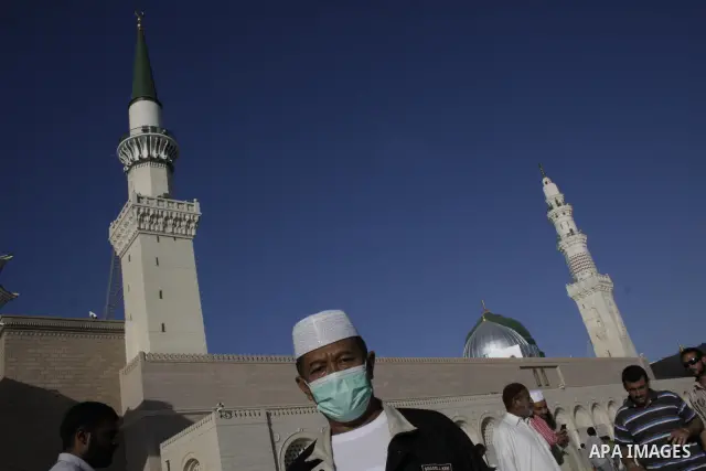 Muslim pilgrim,wearing a mask for protection against swine flu, walks outside the Prophet Mohammed Mosque in the Saudi holy city of Medina on November 12, 2009. More than three million Muslims are expected to converge on...