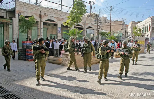 Israeli soldiers guard Jewish settlers as they walk in the West Bank city of Hebron on November 14, 2009.Photo by Najeh Hashlamoun