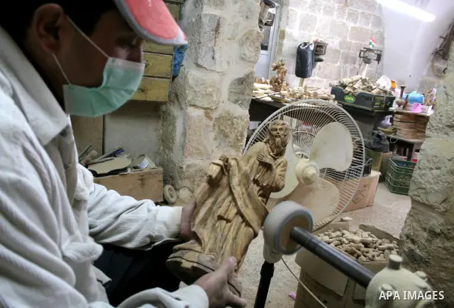 A Palestinian carpenters operates a machine carving wooden effigies of the the Holy Family in a workshop in the West Bank town of Bethlehem December 11, 2009, ahead of Christmas. Photo by Najeh Hashlamoun