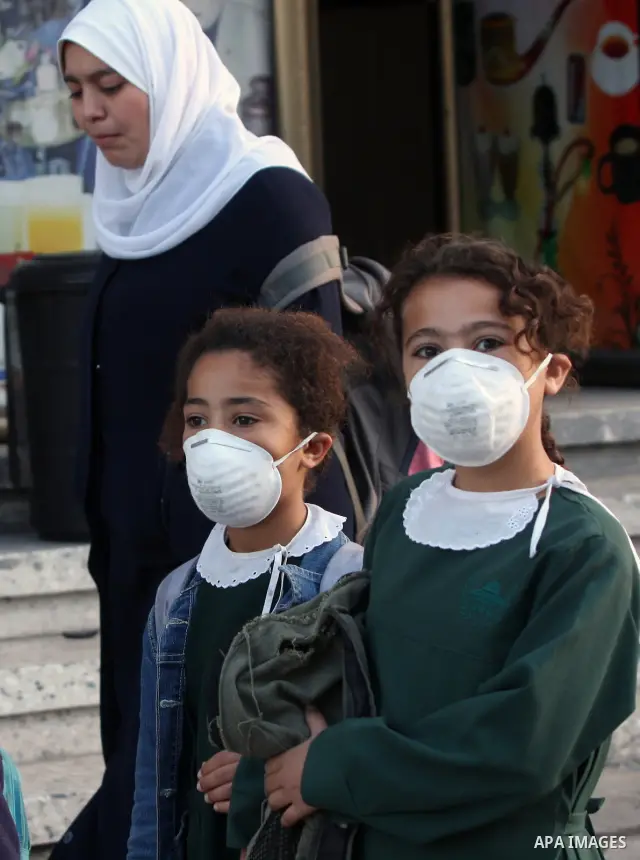 Palestinians wear face masks on a street in Gaza city for fears of A/H1N1 virus in Gaza city on Dec 13, 2009. The virus killed a sixth Palestinian victim since it was discovered in the Gaza Strip on Sunday. photo by Wiss...