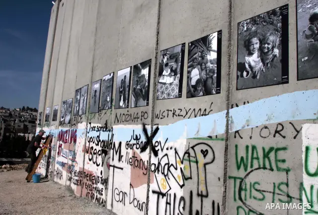 An Italian tourist depicting paint pictures on the Israeli controversial separation barrier in the West Bank city of Bethlehem on December 28, 2009. Photo by Mohamar Awad