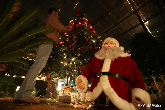 Palestinian decorates a tree at a park in Gaza city on Dec 31,2009 in preparation for celebrating the new year. Like this day a year ago, a large-scale Israeli military operation was ongoing in the Gaza Strip. Photo by W...