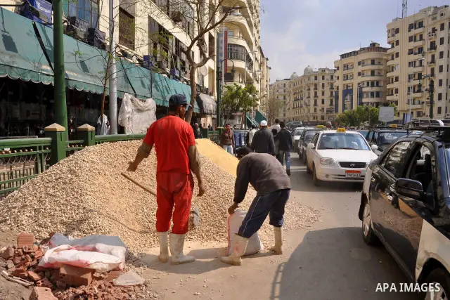 Egyptians labourers work in front a building in Cairo, Egypt, Tuesday, Feb. 8, 2011. Protesters appear to have settled in for a long standoff, turning Tahrir Square into a makeshift village with tens of thousands coming...