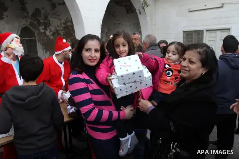 Palestinian Christians carry gifts during a ceremony ahead of Christmas at the Church of Saint Porphyrius, in Gaza City on 22 December 2013. Photo by Mohammed Asad